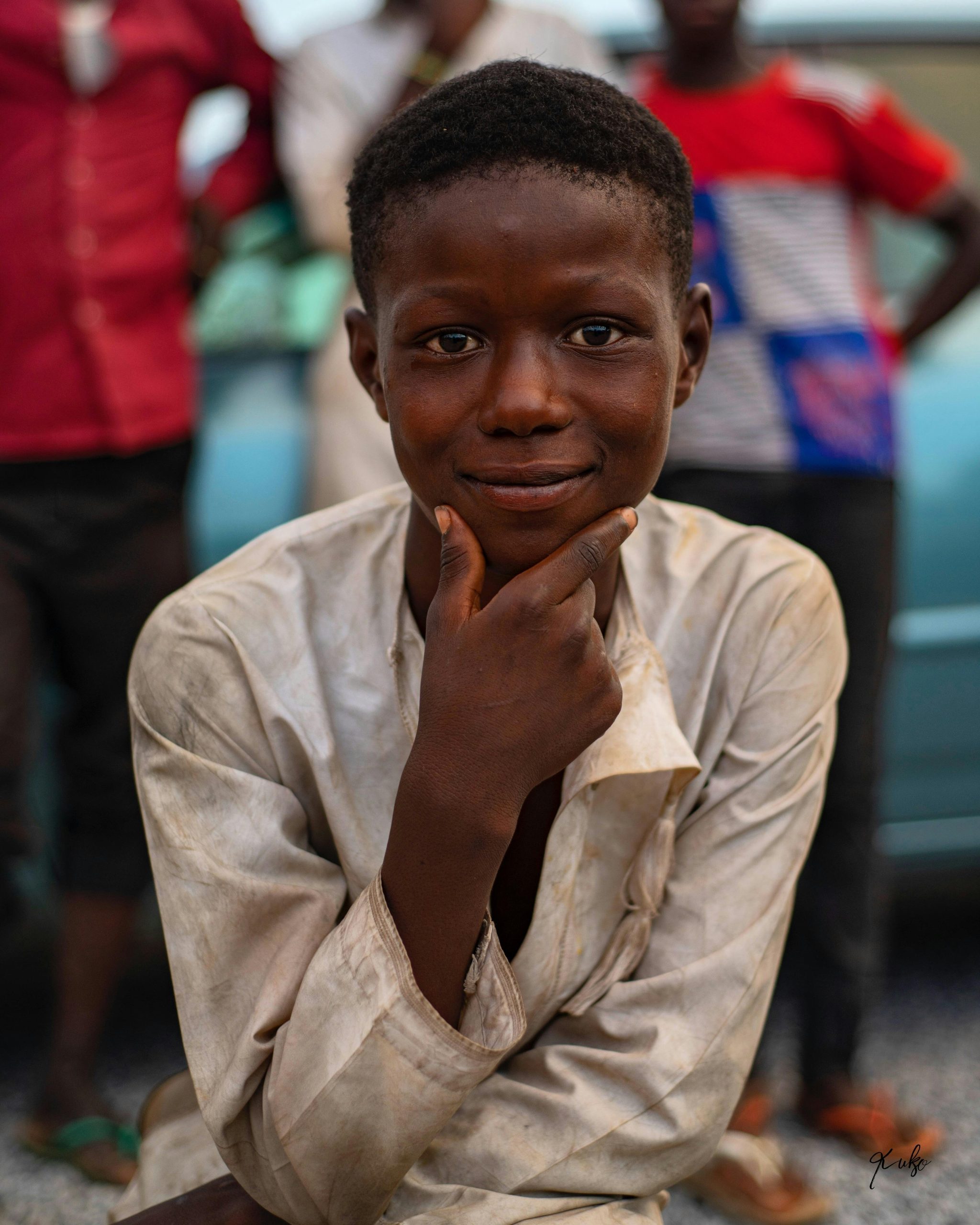 A cheerful young boy poses with a thoughtful expression outdoors in Abuja, Nigeria.